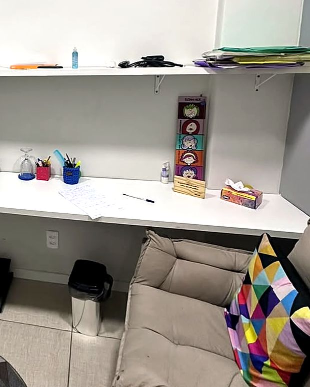Segunda sala de atendimento da clínica, com sofá, escrivaninha e prateleiras.